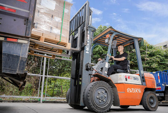 a worker driving a forklift to stack packaging boxes