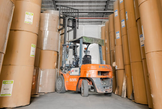 huge rolls of paper in a warehouse with a forklift